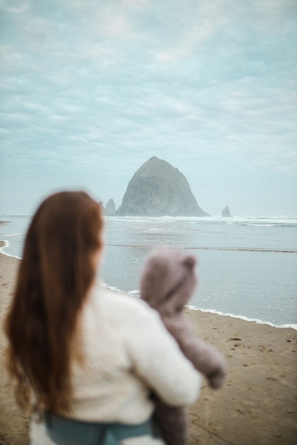 2 women sitting on beach shore during daytime