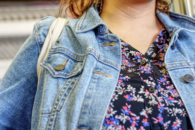 Close-up of a woman wearing a bright patterned blouse with rounded star logo pin.