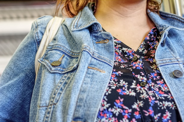 Close-up of a trendy woman happily trying on a floral blouse indoors.