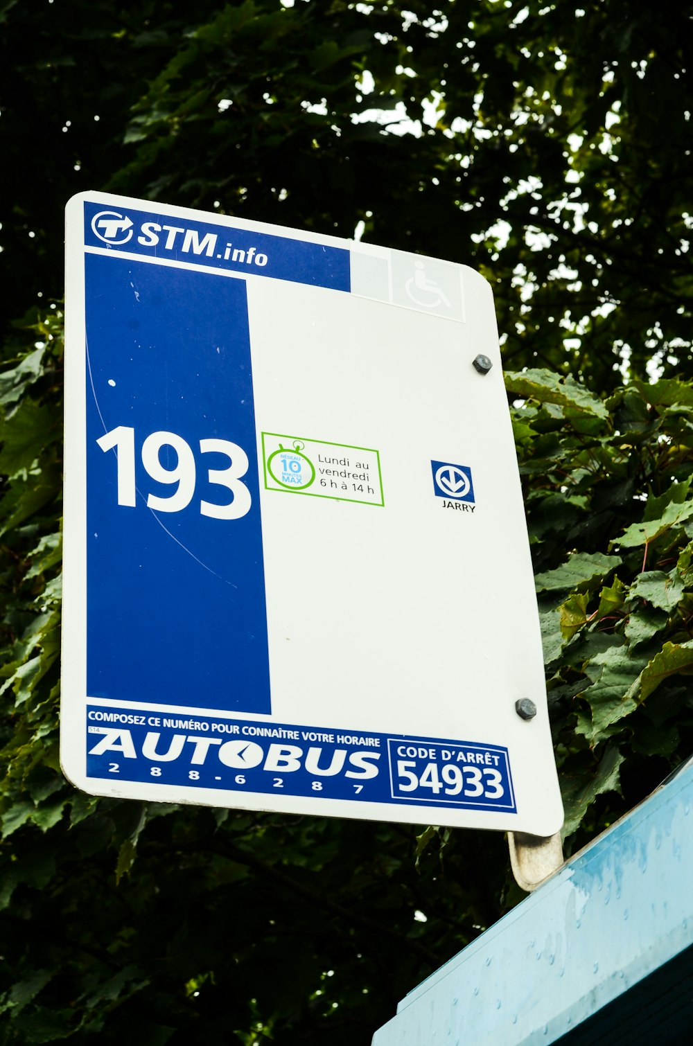 a blue and white street sign with trees in the background