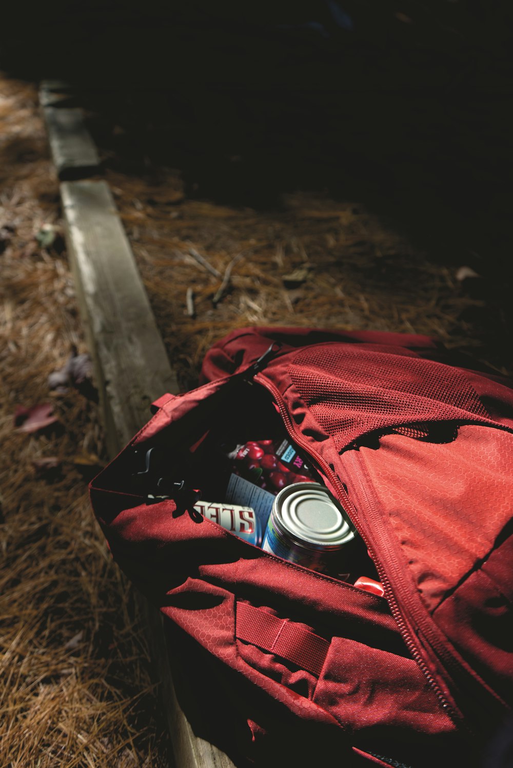 red and black backpack on brown wooden bench