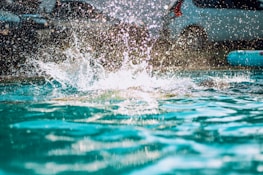 A water tanker truck spraying and filling a swimming pool on a sunny day.