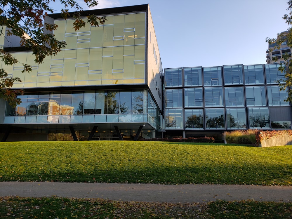 Bâtiment en verre près d’un champ d’herbe verte pendant la journée