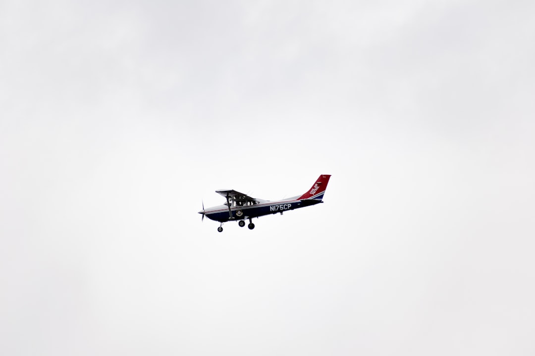 white and red airplane in mid air, An old civilian propeller plane flying on a gray cloudy sky during autumn.