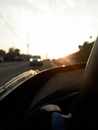 A sleek sedan driving on an open road at sunset with warm golden light.