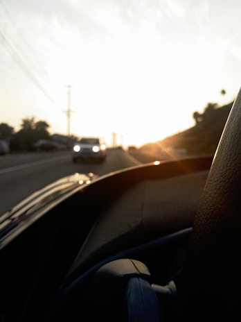 An instructor and student smiling inside a car during a driving lesson at sunset.