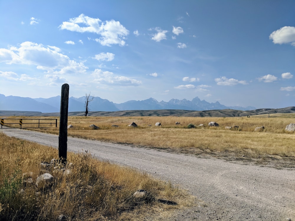 brown wooden fence on brown grass field under blue sky during daytime