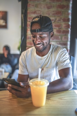man in white and gray striped crew neck t-shirt wearing black cap sitting beside brown