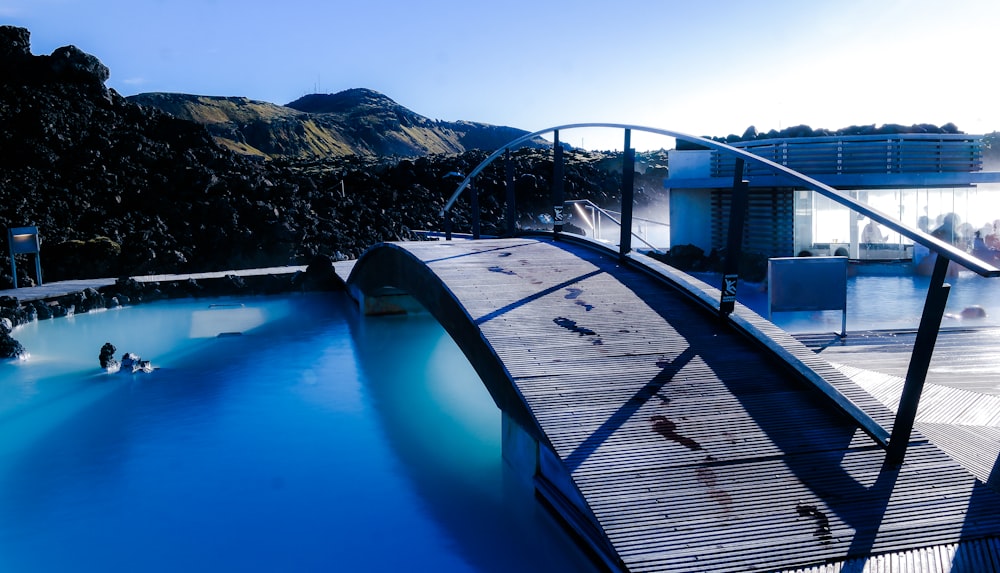 blue and black swimming pool near brown wooden dock during daytime