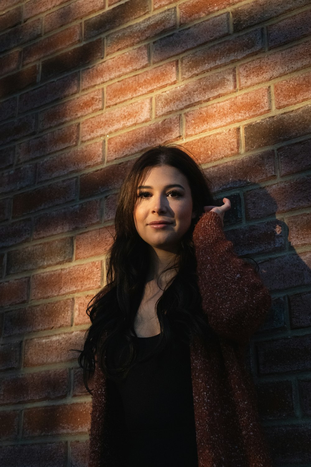 woman in brown fur coat leaning on brown brick wall