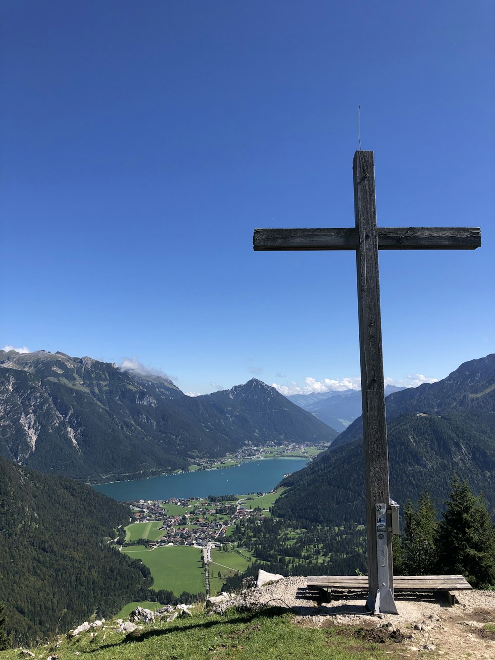 brown wooden cross on green grass field near green mountains under blue sky during daytime