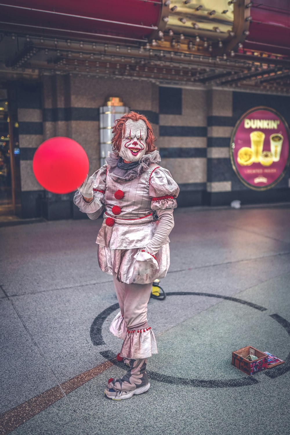 woman in brown and white stripe coat holding red balloon