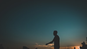 A silhouette of a woman confidently walking away in high heels at sunset, embodying strength and determination.