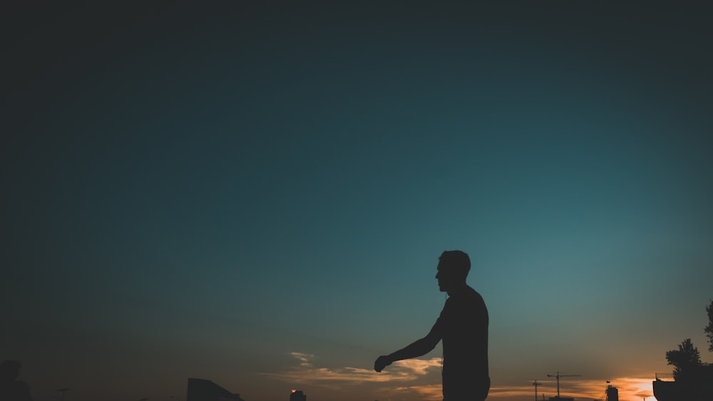 silhouette of man and woman standing during sunset
