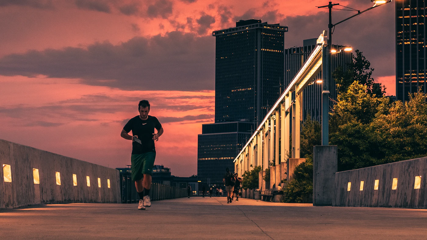 Runner crossing a city bridge at sunset