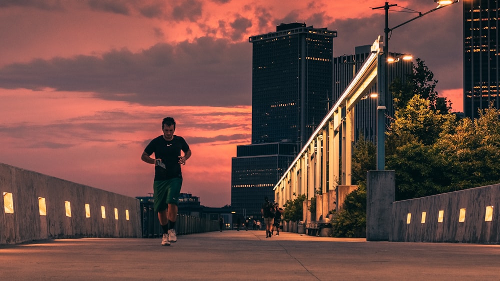 man in black jacket and black pants standing on sidewalk during sunset