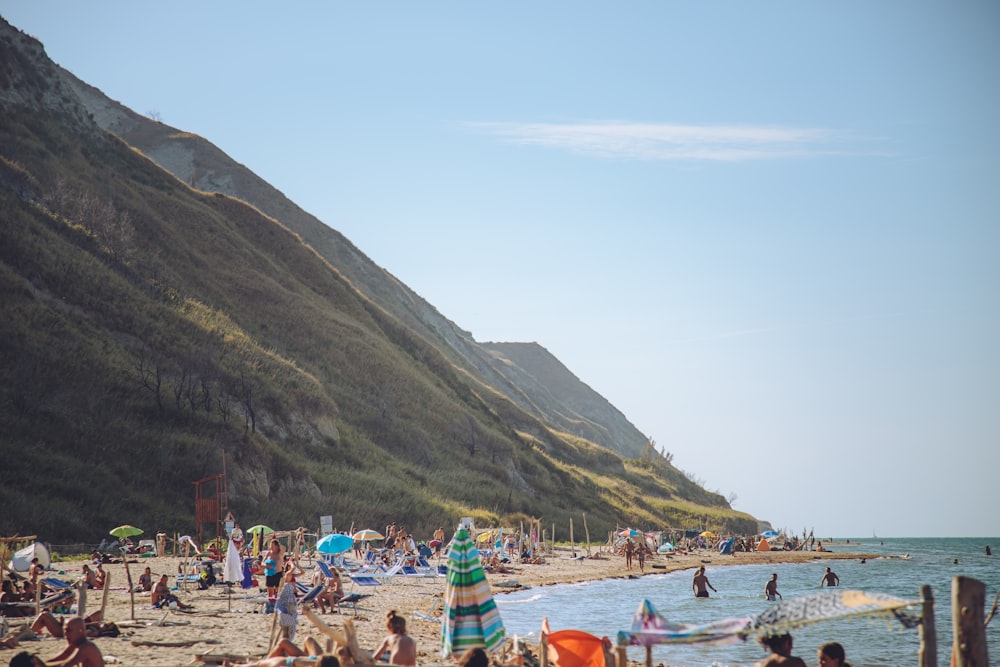 people on beach near mountain during daytime