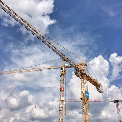 A tall yellow tower crane operated by Octagon Enterprises against a clear blue sky at a bustling construction site.