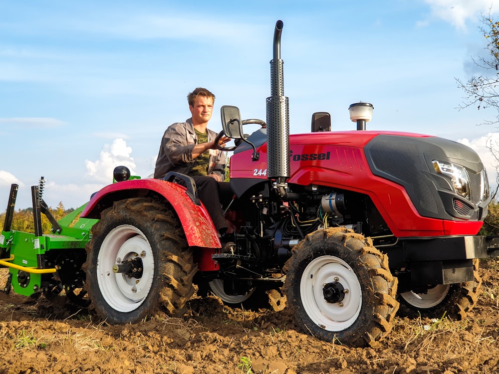 man in brown jacket riding red tractor