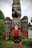 A native Alaskan storyteller in traditional attire speaking to a small group near a totem pole on Prince of Wales Island.