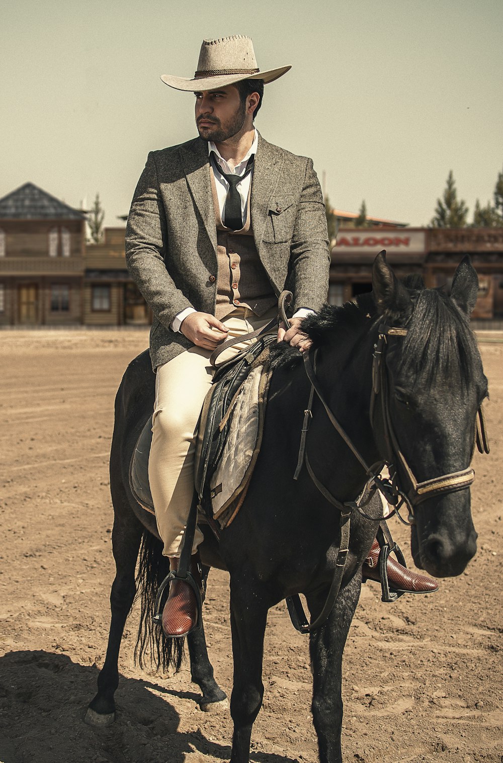 man in gray coat riding black horse during daytime