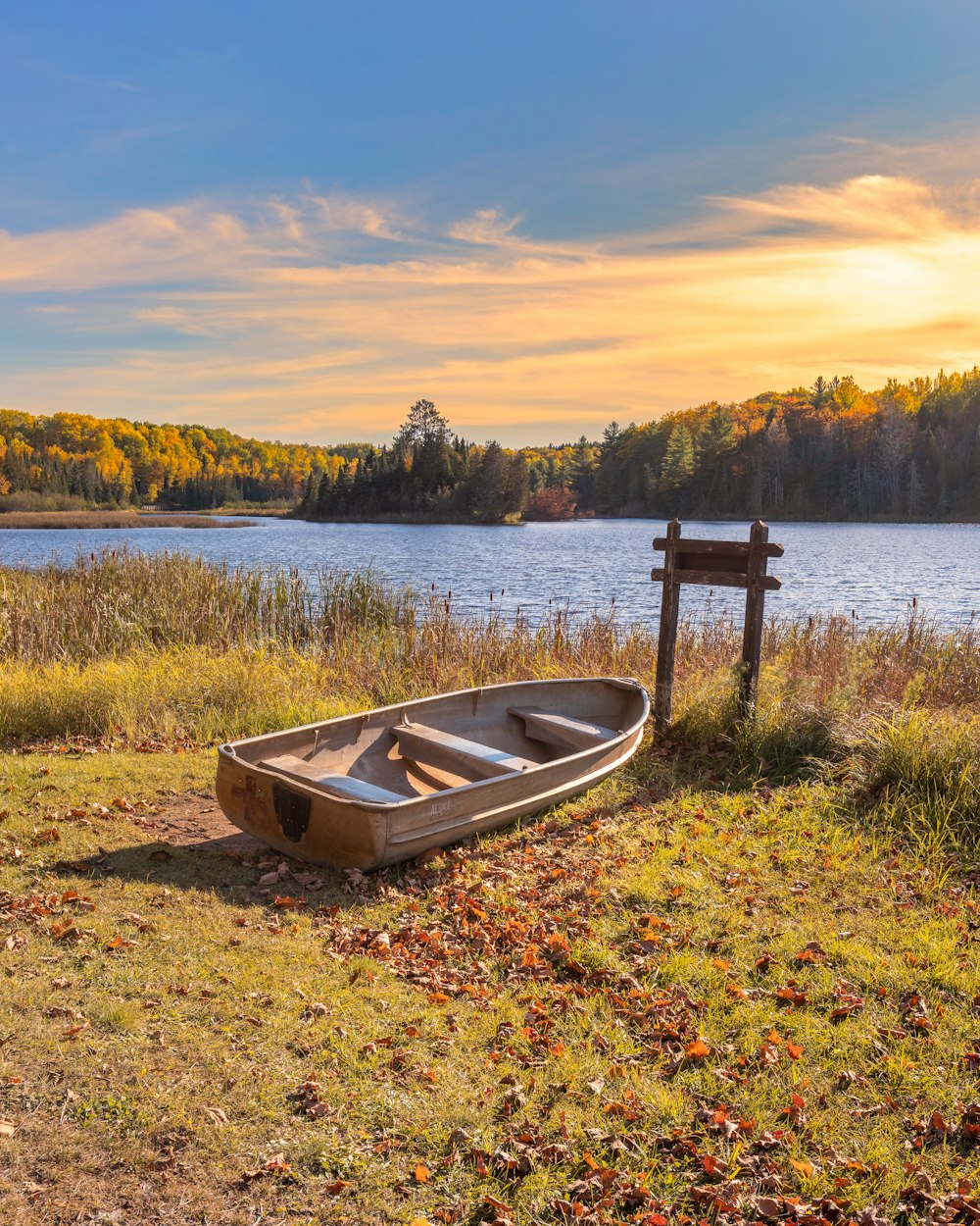white and brown boat on green grass near lake during sunset
