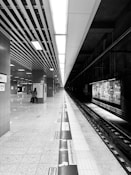grayscale photo of people walking on train station