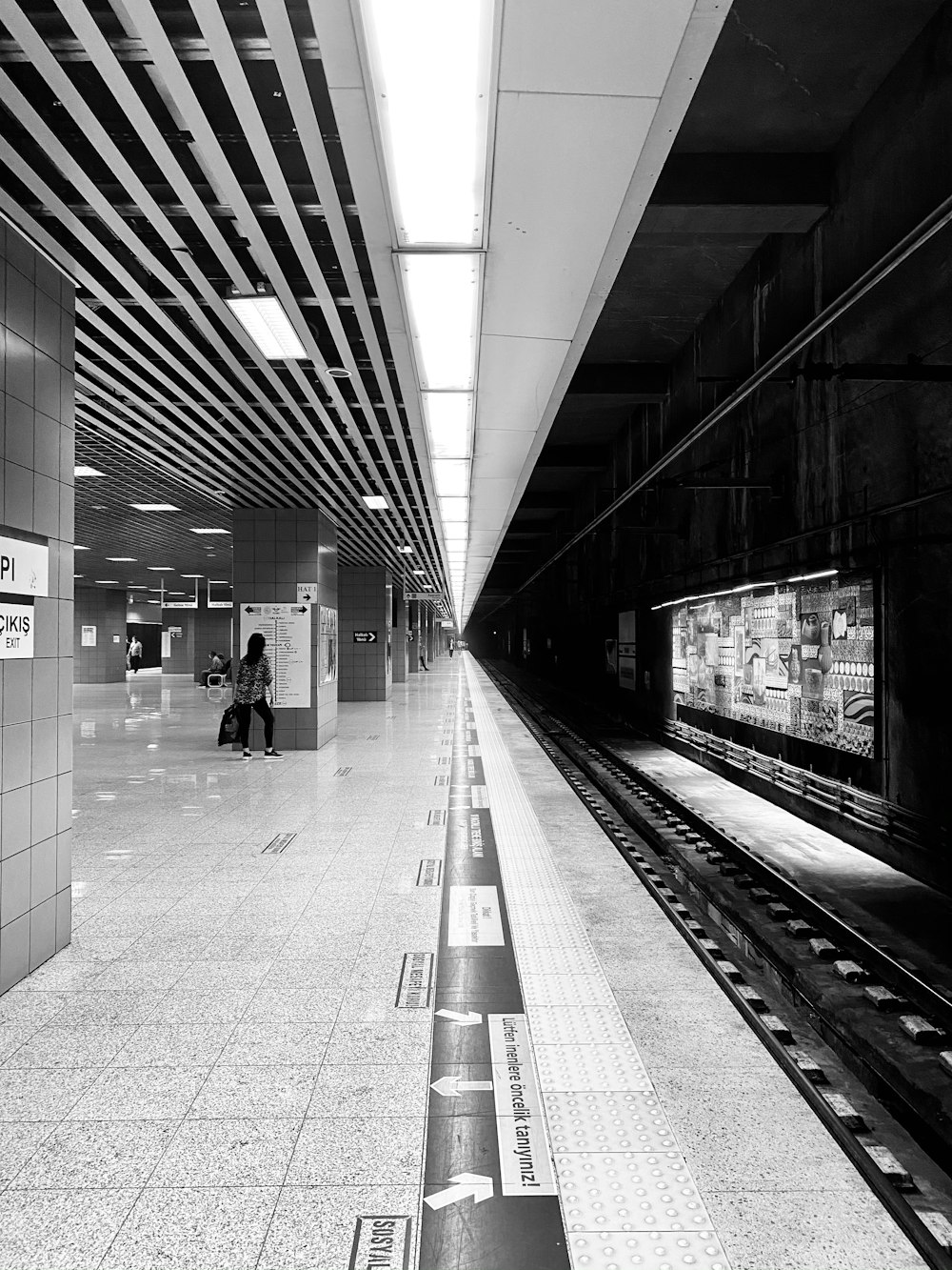 foto em tons de cinza de pessoas andando na estação de trem