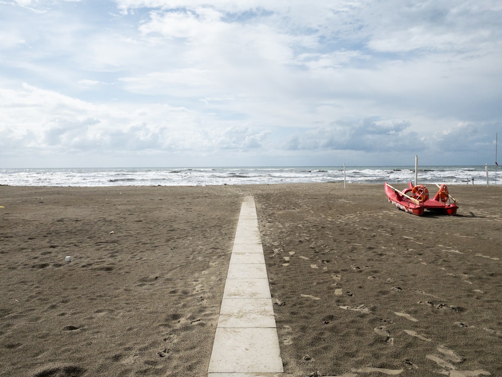 barca rossa sulla riva della spiaggia durante il giorno