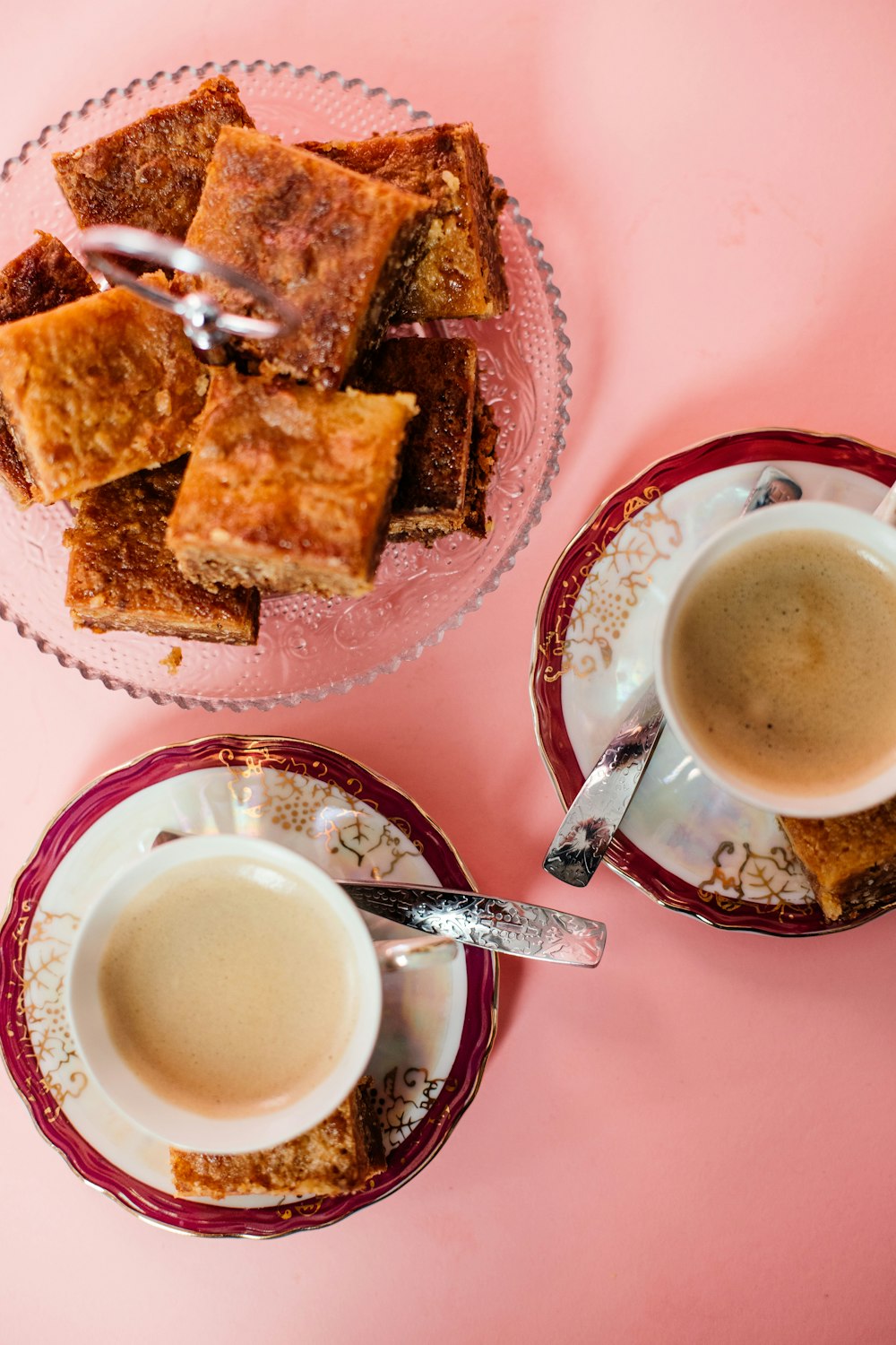 white ceramic mug with coffee beside brown bread on white and red ceramic plate