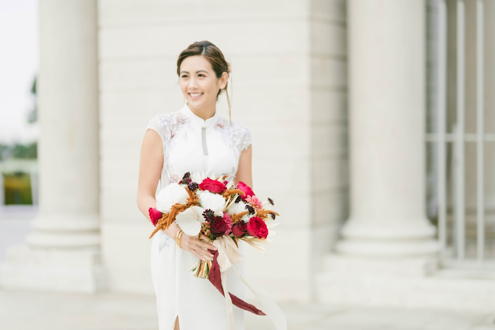 woman in white sleeveless dress holding bouquet of flowers