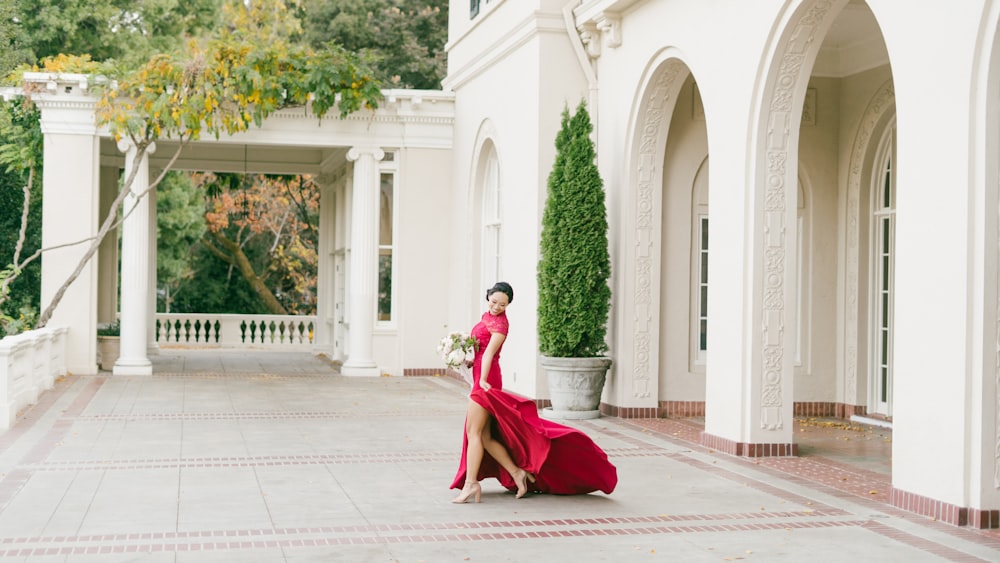 a woman in a red dress is walking in front of a building