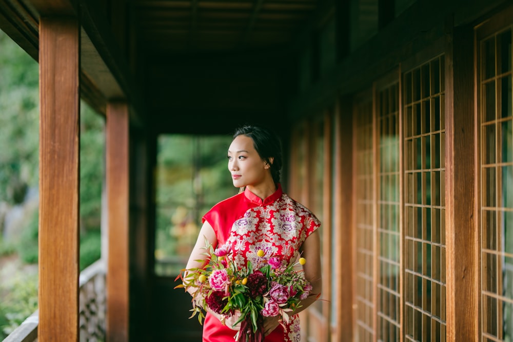 woman in red and white floral dress holding bouquet of flowers