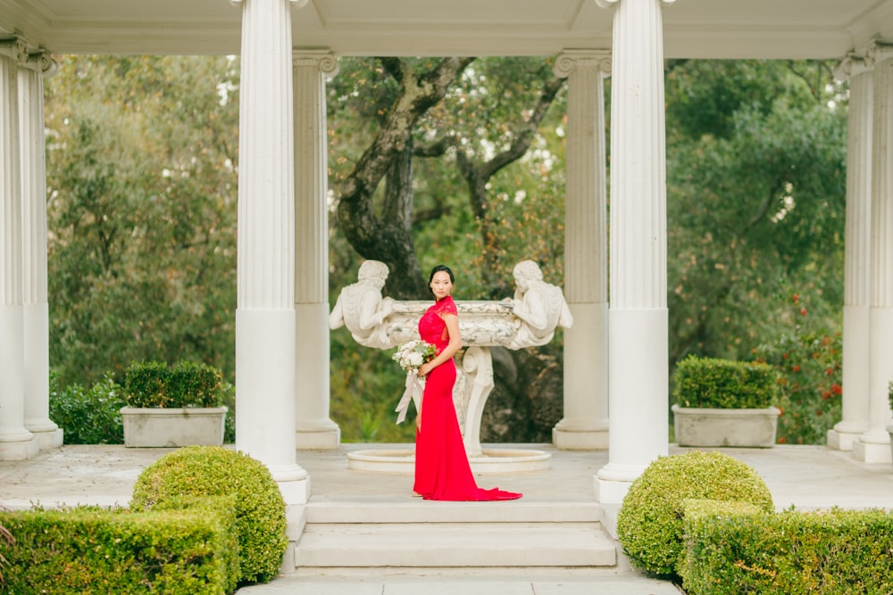 woman in red dress standing on white concrete staircase