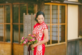 woman in red and white floral dress holding bouquet of flowers