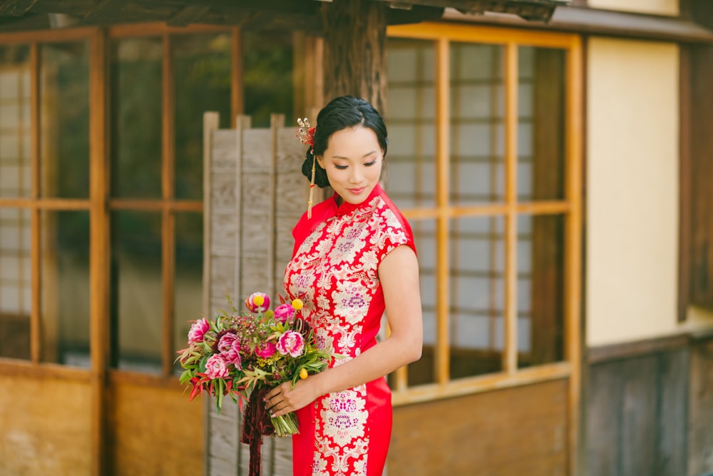 woman in red and white floral dress holding bouquet of flowers