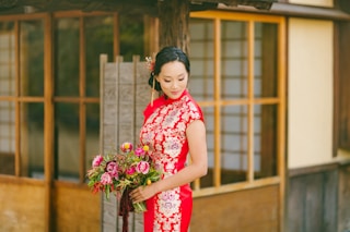 woman in red and white floral dress holding bouquet of flowers