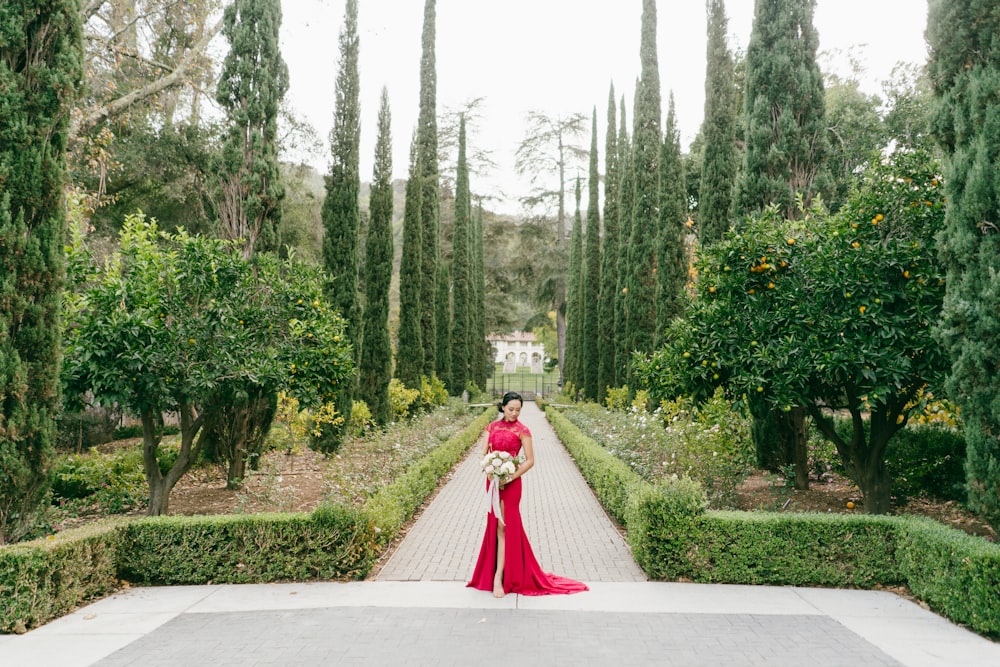 woman in red dress walking on gray concrete road during daytime