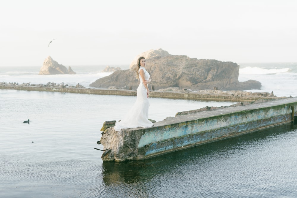 woman in white dress standing on brown wooden dock during daytime