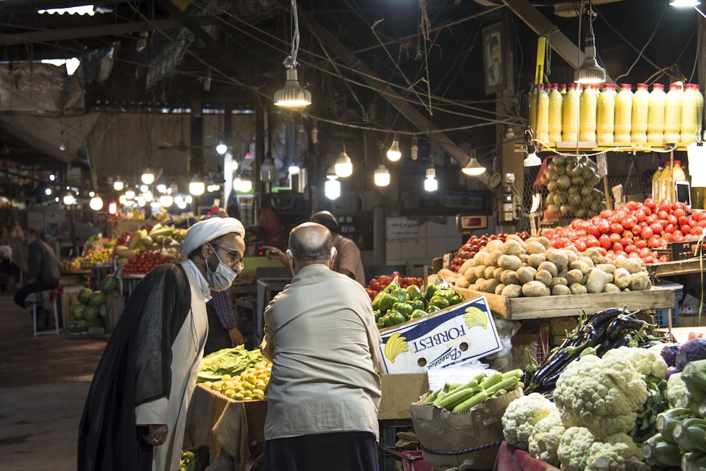 man in gray shirt standing in front of fruit stand