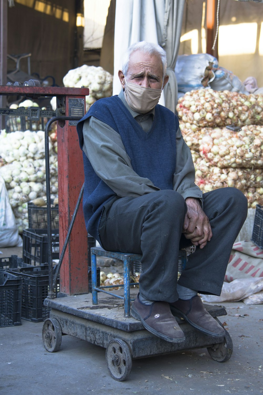 man in blue jacket sitting on red plastic chair