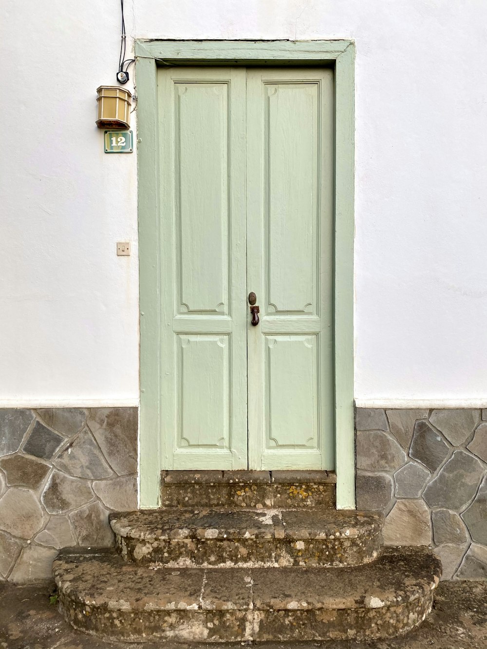 緑と黒のドアノブ付きの白い木製ドア