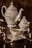 A beautifully crafted set of porcelain teaware consisting of a teapot, a sugar bowl, and a teacup with a saucer. The set features delicate floral patterns. Warm fairy lights are artistically arranged around the teaware, adding a cozy and enchanting atmosphere.