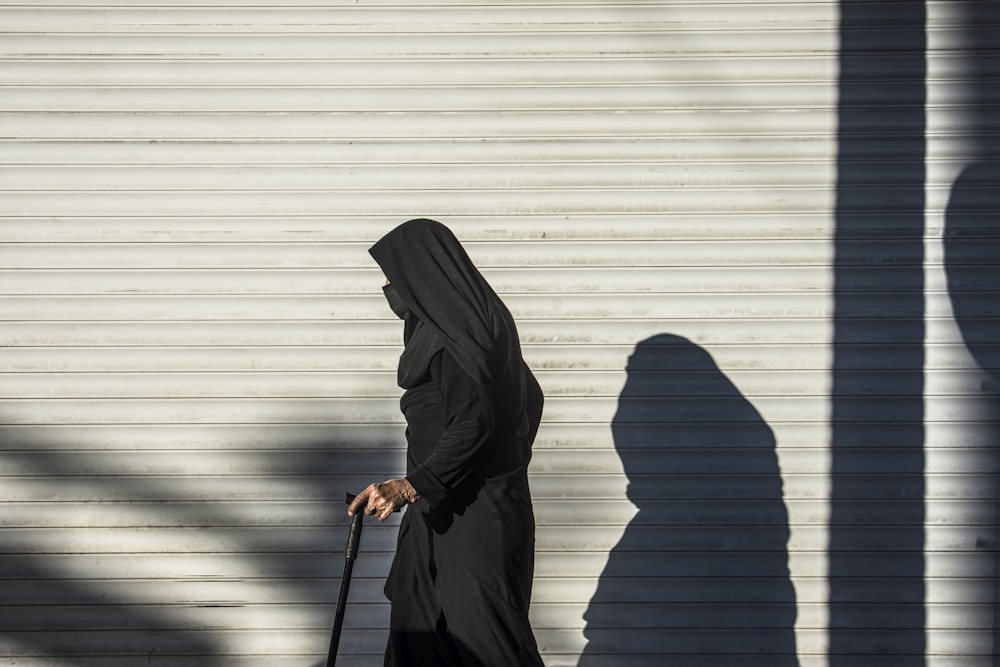2 person wearing black hijab standing in front of white wall