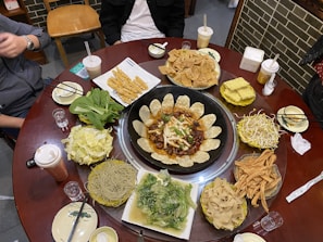 A group of friends sharing various dishes at a table in a food court.