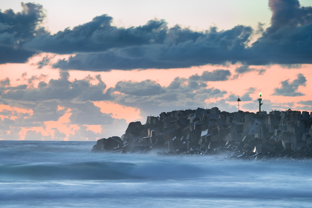 ocean waves crashing on rocky shore under cloudy sky during daytime