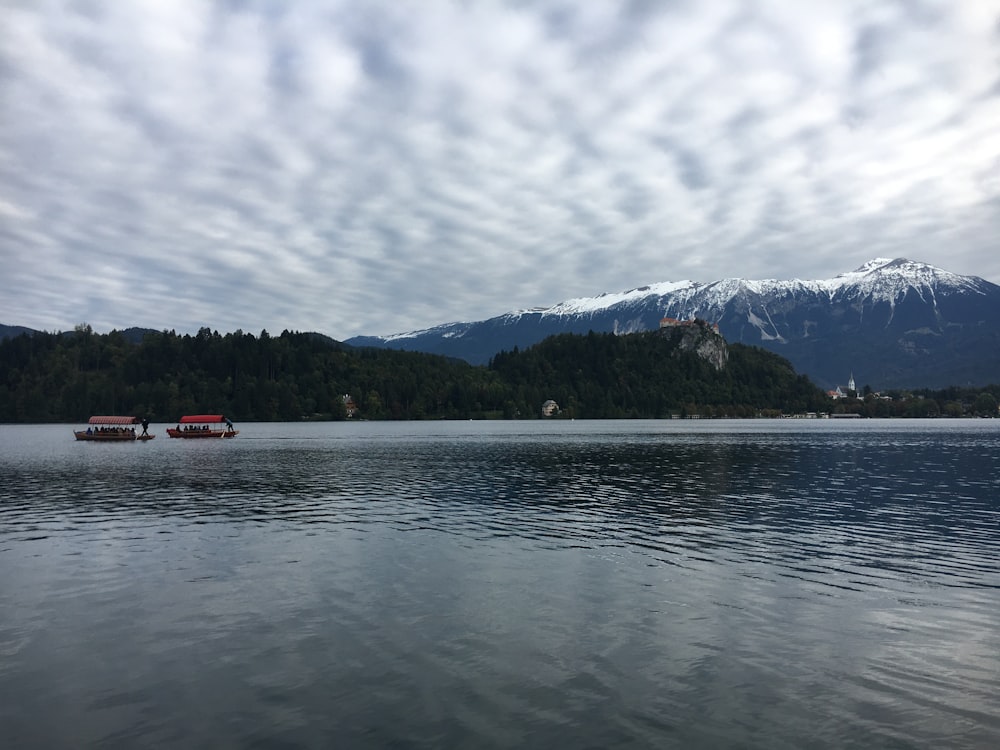 boat on water near mountain under cloudy sky during daytime