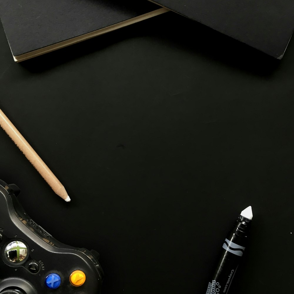 black xbox one game controller beside brown pencil
