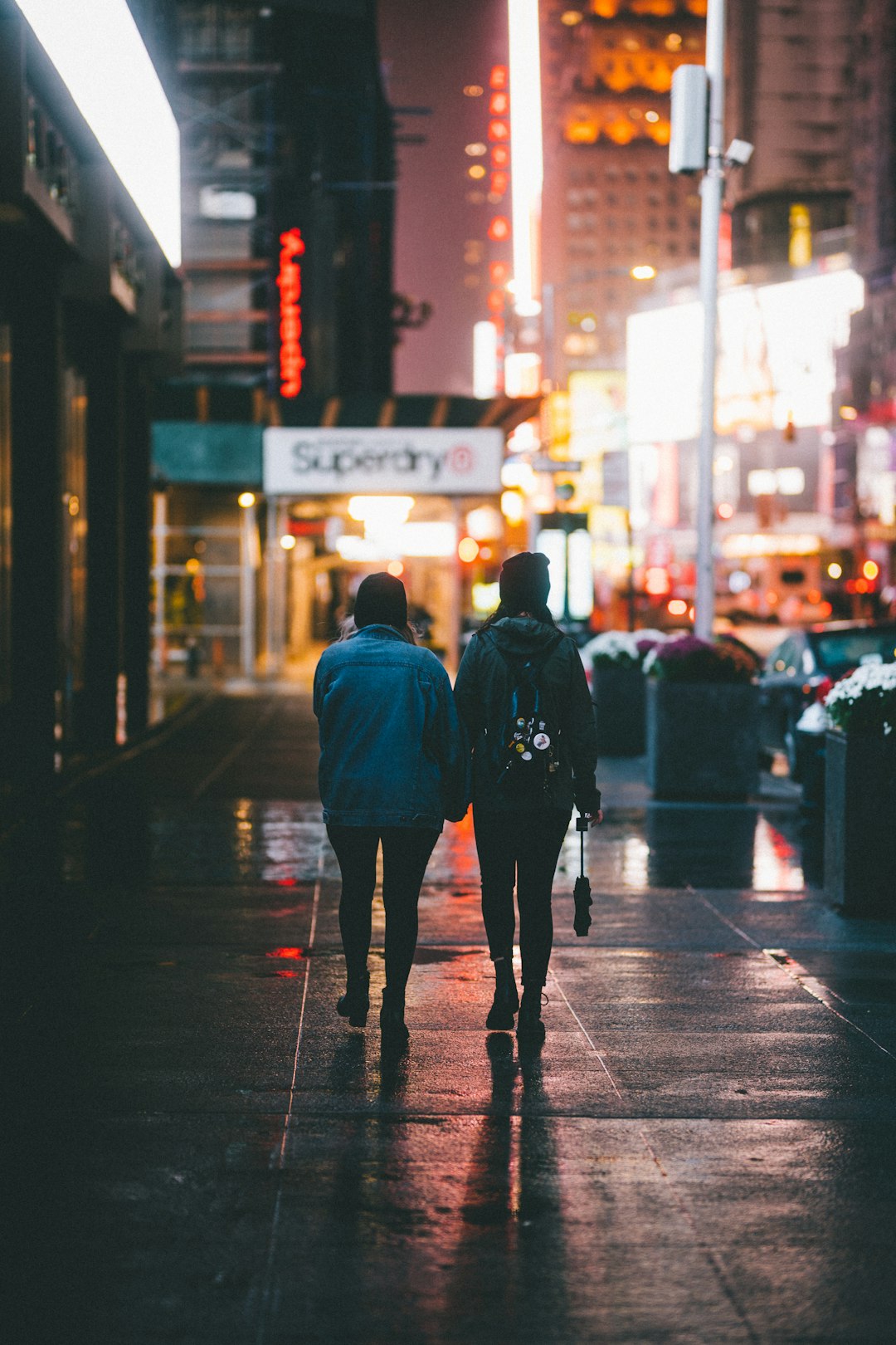 man in blue jacket walking on sidewalk during night time