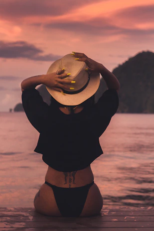 Femme portant un chapeau face à la Méditerranée au coucher du soleil, soirées REF à la Plage